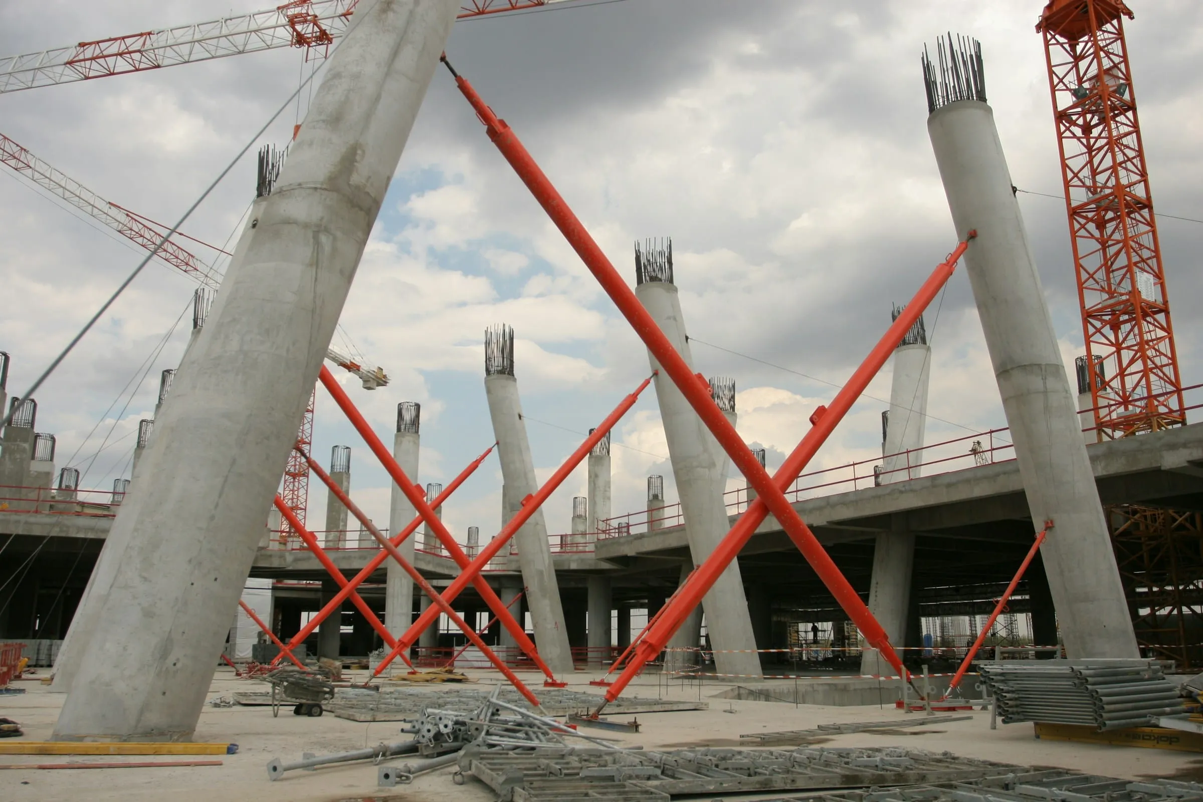 Concrete columns held by orange temporary bracing on a large construction site